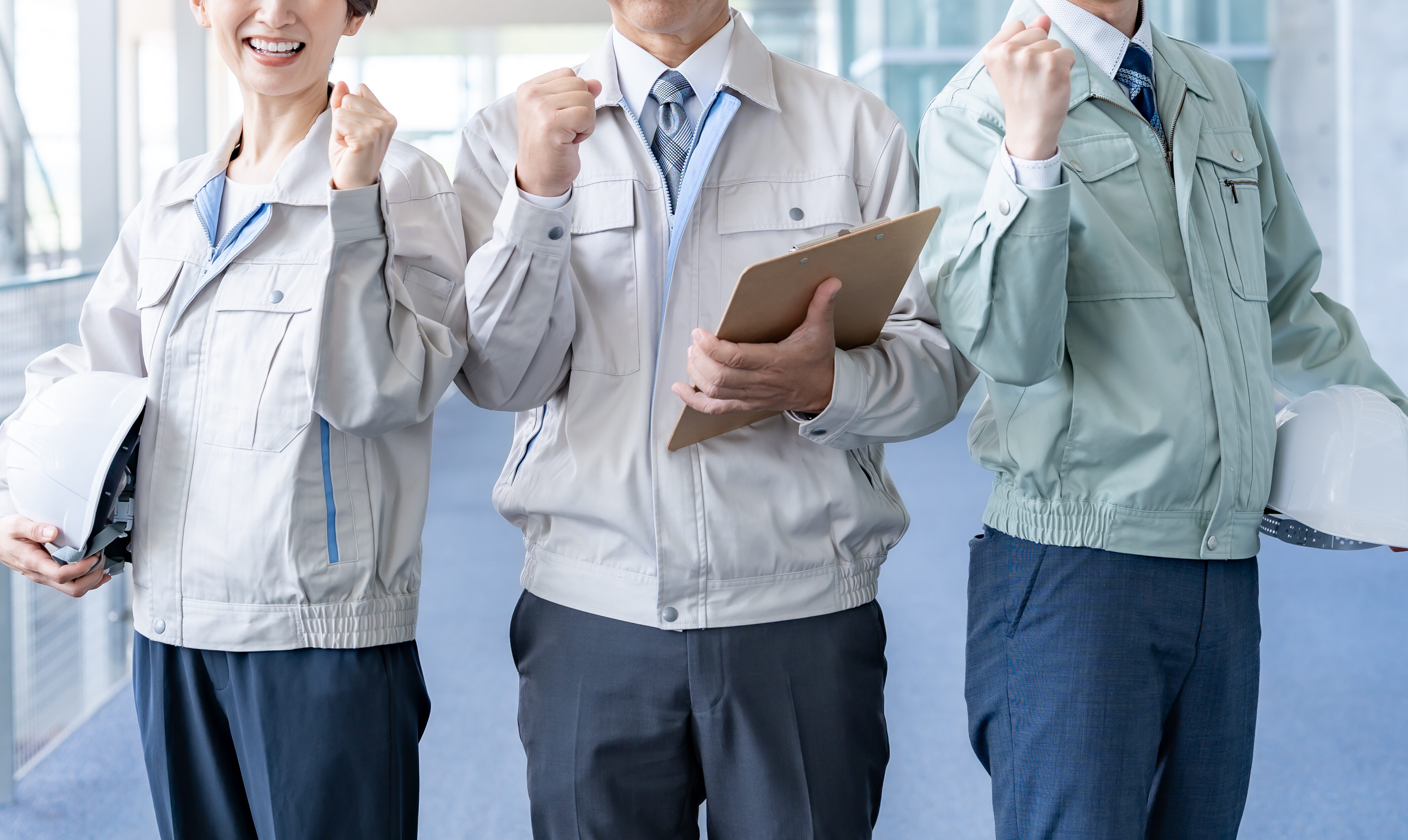 ガッツポーズをする作業着を着た男女